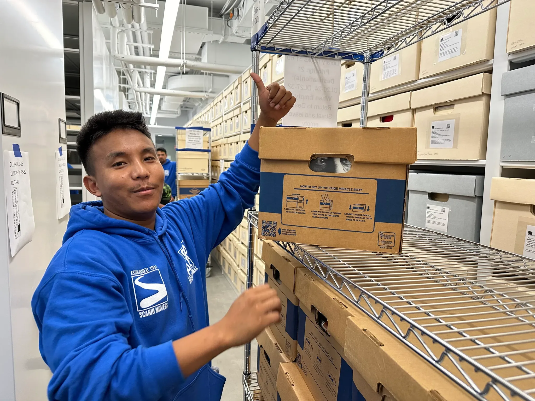 A Scanio team member at our warehouse, organizing client belongings on managed shelving
